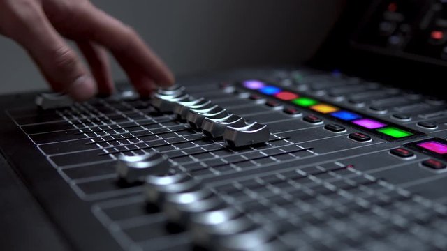 Man works on a professional electronic audio mixer. A control panel for tuning sound channels