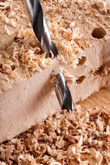 Drilling holes in raw wood. Carpentry drill in a carpentry workshop.