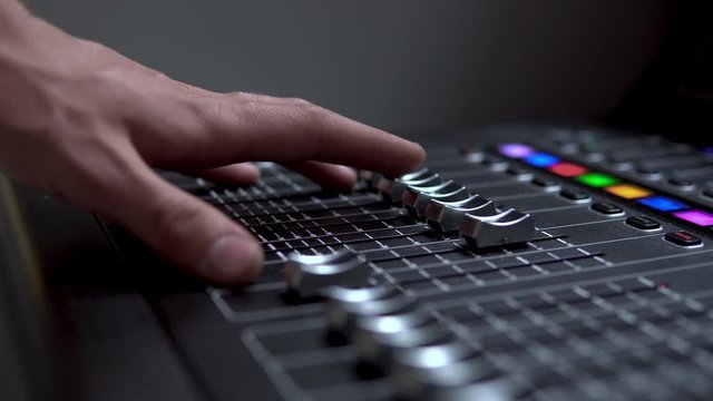 Man works on a professional electronic audio mixer. A control panel for tuning sound channels