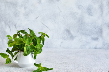 Fresh, green mint on the kitchen table on a concrete background.