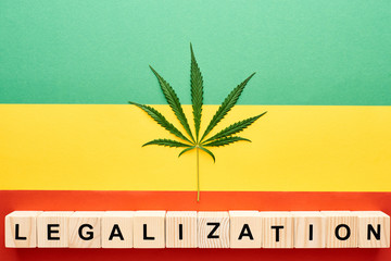 top view of cannabis leaf and wooden blocks with legalization lettering on Rastafarian flag...