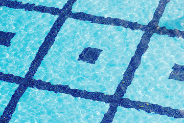 Fototapeta na wymiar Water ripple on a background of blue tiles in the pool. View from above.