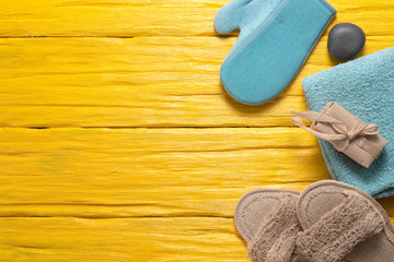 Soap, towel, slippers and bath mitt on a yellow wooden background with a copy space. Hygiene flat lay background.