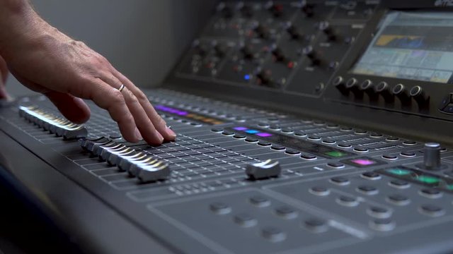 Man works on a professional electronic audio mixer. A control panel for tuning sound channels