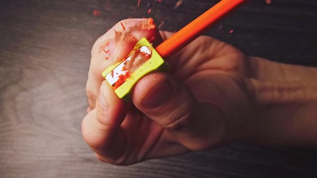 Overhead slow motion of sharpening the pencil in sharpeners on top of the wooden table