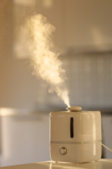 Close up of aroma oil diffuser on the table at home, steam from the air humidifier, copy space. Ultrasonic technology, increase in air humidity indoors, comfortable living conditions. 