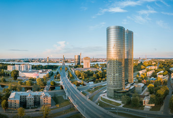 Naklejka na ściany i meble Panoramic, aerial view over Riga city. Modern buildings, roads, and other infrastructure. Cable bridge leading to iconic old town panorama in vivid sunset colors. 