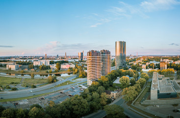 Fototapeta premium Panoramic, aerial view over Riga city. Modern buildings, roads, and other infrastructure. Cable bridge leading to iconic old town panorama in vivid sunset colors. 