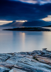 Sun bursting thru the dark sky over Landego in Bodo, Norway
