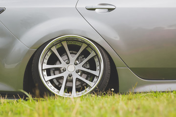 tuned alloy wheels with a wide rim on an lowered silver car standing on the grass.