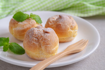 Cream puffs on white plate.