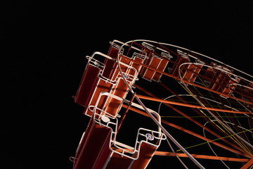 Obraz na płótnie Canvas Empty Ferris wheel no people at night illuminated against dark sky low angle view at the fun fair