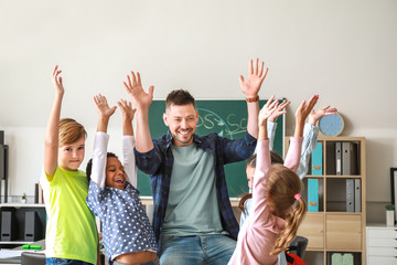 Happy children with teacher in classroom