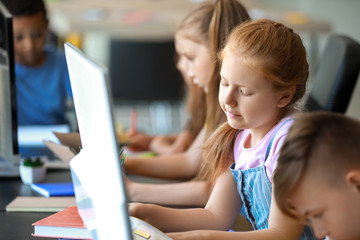 Cute little pupils during lesson in classroom