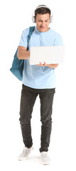 Portrait of young student with laptop and headphones on white background