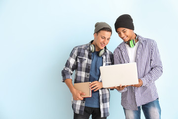 Portrait of young students with laptop on color background