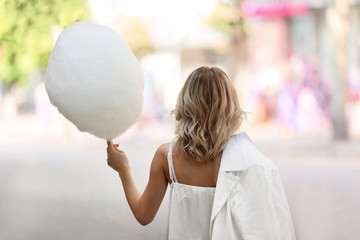 Woman with sweet cotton candy outdoors, back view