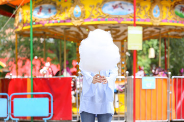 Woman with sweet cotton candy in amusement park