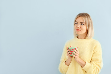 Portrait of beautiful woman drinking coffee on color background