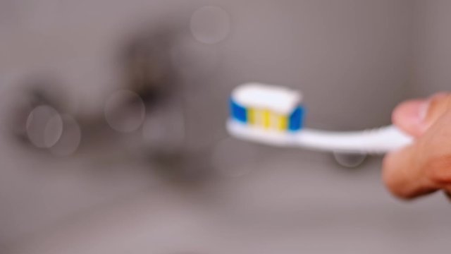 Young man squeezing toothpaste onto the toothbrush in bathroom. Daily life morning. Isolated. Close up
