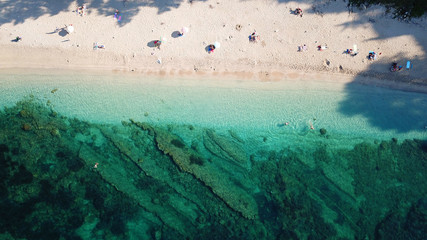 Aerial top view photo of sun beds and umbrellas in popular tropical paradise deep turquoise...