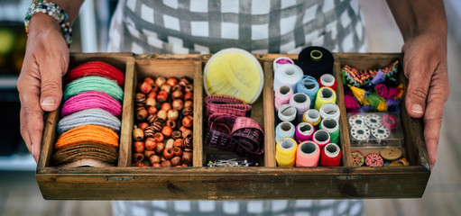 Close up of caucasian adult woman showing a sailor kit at home - colors and beads and cords to repair clothes hand made - artisan. and people at work concept