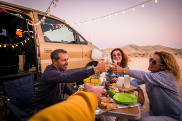 Happy people group of friends toasting and enjoying the travel vacation together - cheerful. womanandman with food in outdoor leisure activity - modern van and ocean in background