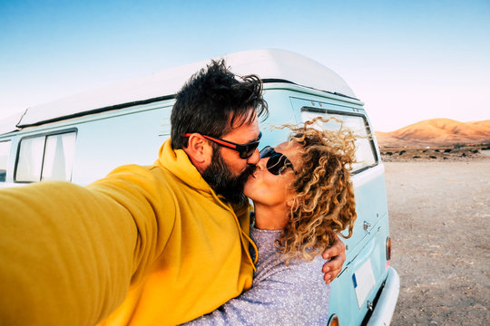 Love and relationship concept with couple of traveler with old vintage van kissing and taking a selfie picture -alternative lifestyle and. vacation with beautiful woman and man outdor