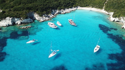 Aerial drone photo of tropical paradise turquoise beach of Voutoumi with sail boats docked in island of Antipaxos, Ionian, Greece