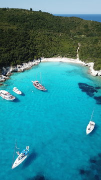 Aerial drone photo of tropical paradise turquoise beach of Voutoumi with sail boats docked in island of Antipaxos, Ionian, Greece