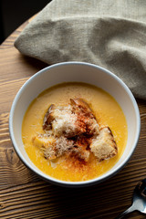 Classic french creamy cheese soup with wheat croutons on a rustic-style wooden table - a perfect autumn comfort food
