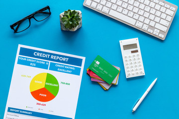 credit report with credit cards and keyboard on banker work place blue background top view