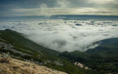 Above the clouds. High mountains, covered by a veil of clouds.