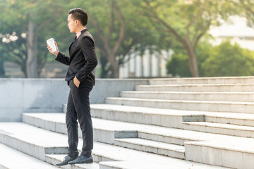 Young Malay Business Man on his Smartphone with a cup of coffee.