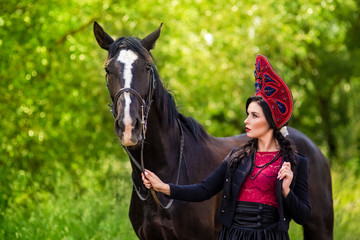 Gorgeous Fashion Caucasian Model in Kokoshnik Posing With Thoroughbred Horse Against Nature Background Outdoors.