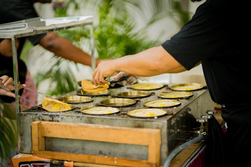 A hawker preparing griddle pancake, a snack of crispy flour and egg mixture and layered with finely...