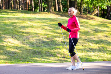 Portrait of Sportive Senior Woman Doing Nordic Walking in Park.