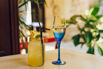Glass of white wine and yellow cocktail on the table