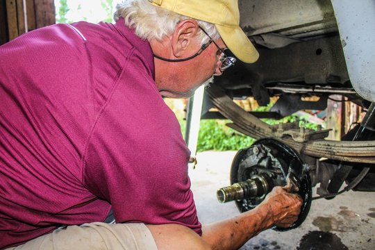 Active Senior Man working in his garage on his truck wheel assembly