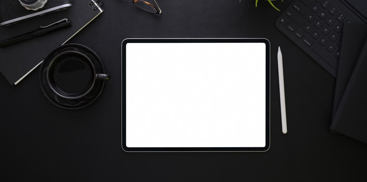 Top view of blank screen tablet on black desk background