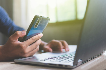 Business man hand holding smart mobile phone, using credit card for online shopping with laptop computer and digital tablet on table. Cyber concept
