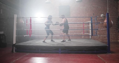 Female boxer with trainer using focus pads