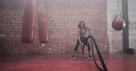 Mid adult female working out with battle ropes