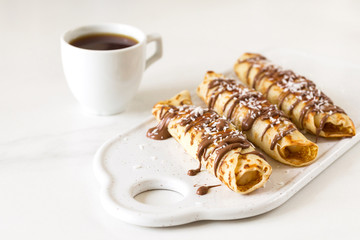 Pancakes rolls with cottage cheese and chocolate, coffee. Breakfast