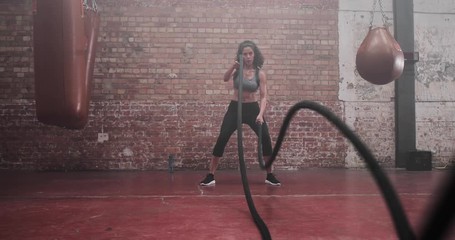 Mid adult female working out with battle ropes