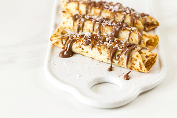 Pancakes rolls with cottage cheese and chocolate, coffee. Breakfast