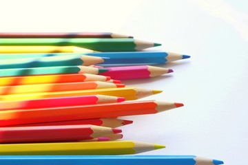The sun's rays fall on the colored pencils lying on a white background. Color Therapy Concept.Copy space for text, with selective focus.
