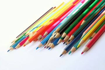 The sun's rays fall on the colored pencils lying on a white background. Color Therapy Concept.Copy space for text, with selective focus.