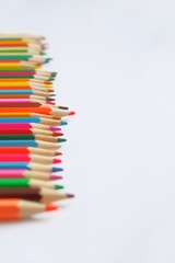 Mixed colored pencils on a white background for learning to draw in school laid out in a row .  With selective focus, copy spase for text.