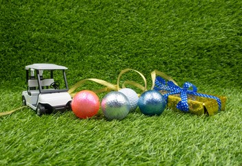 Merry Christmas to golfer with golf balls and buggy on green grass.